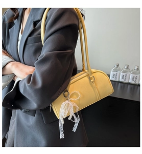 Detail of yellow lychee leather shoulder bag with lace bow and pearl charm accents