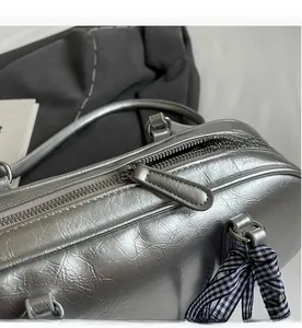 Close-up of a silver pleated handbag showing smooth metal zipper and blue gingham ribbon
