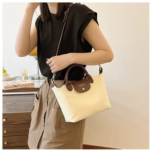 Cream nylon tote bag detail with brown leather handles and adjustable shoulder strap