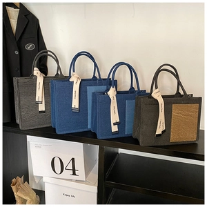 Multiple colors of minimalist felt tote bags displayed on a sleek black shelf setup