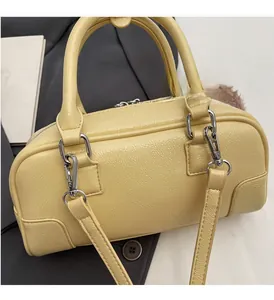 Detail of cream-yellow leather boston bag with furry pom-pom charm and silver hardware