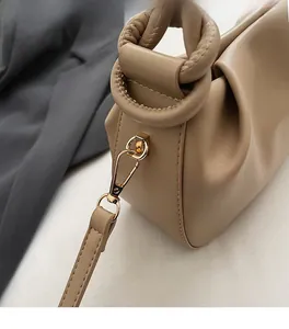Detailed macro view of light brown pleated bucket bag with twisted handle and gold hardware
