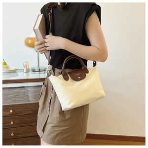Close-up of beige nylon tote bag with brown leather handle and detachable strap