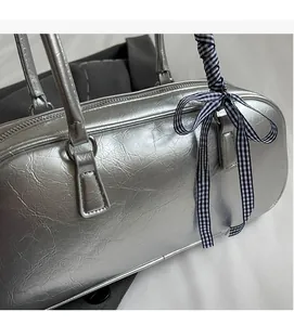Detail of silver metallic Boston bag with wrinkled texture and blue checkered ribbon strap