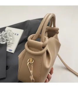 Detailed stitching on beige pleated handbag with gold metal clasp and ring knot