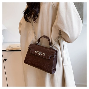 Detail of dark brown crocodile pattern handbag featuring a sleek silver metal long bar lock