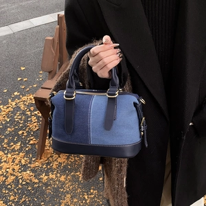 Chic patchwork denim boston bag with blue leather accents and white contrast stitching