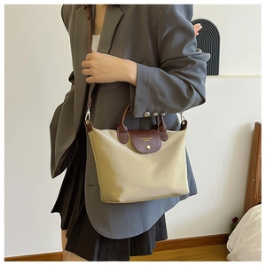 Detail of beige nylon tote bag with brown leather flap handle and detachable shoulder strap