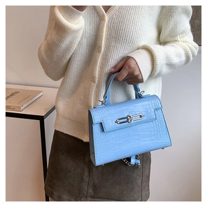Close-up of bright blue crocodile pattern Kelly bag with metal chain detail
