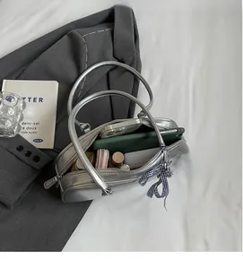 Spacious interior of silver bow-style handbag showing storage for phone and cosmetics