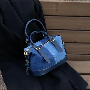 Patchwork denim boston bag with gold hardware on a black coat, urban casual style