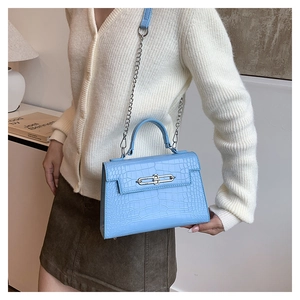 Close-up of light blue crocodile embossed leather handbag with silver chain strap and metal buckle