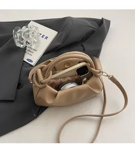 Detail view of the interior capacity showing a wallet and phone in the ruffled beige bag
