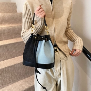 Vintage denim bucket bag with black leather patchwork and elegant gold hardware