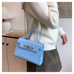 Close-up of light blue crocodile embossed texture and silver metal lock on handbag