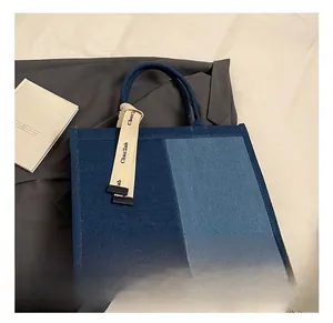 Detail of blue denim patchwork tote bag with stylish contrast stitching and decorative strap
