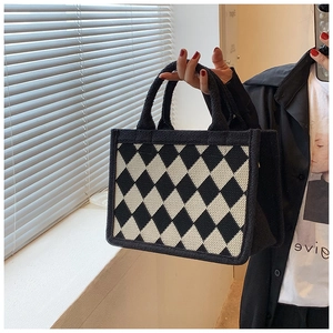 Close-up of black and white diamond lattice knit tote bag with thick wool texture