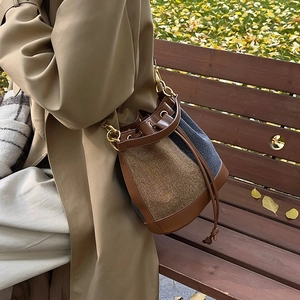 Brown leather and tweed bucket bag with gold chain strap on model in autumn park