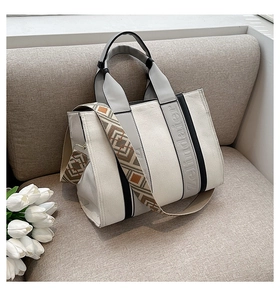 Détail du sac cabas en toile avec bandoulière tissée aux motifs ethniques sur un canapé
