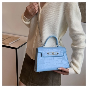 Close-up of light blue crocodile texture handbag with silver metal lock and chain strap