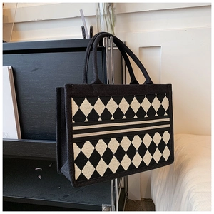 Detail of diamond pattern tote bag with woven rope handles on minimalist hanger