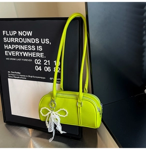 Detail of neon green lychee leather Boston bag with white lace bow and pearl pendant