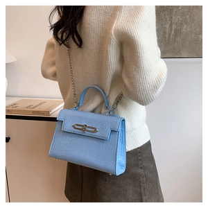 Close-up of light blue crocodile texture handbag with silver lock and chain strap detail