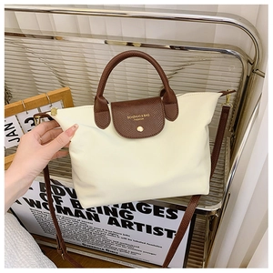 Detail of oxford fabric tote bag with brown crocodile leather flap and gold logo