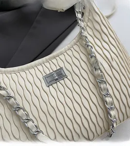 Detail of off-white pleated handbag with silver twist lock and woven chain strap