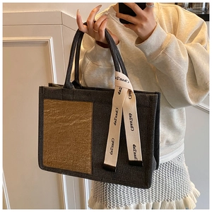 Close-up of charcoal canvas tote bag featuring brown textured panel and ribbon detail