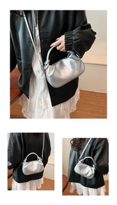 Close-up of silver pleated bucket bag with knotted handle and fashion logo print