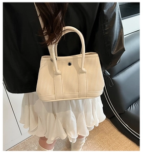 Detail of cream corduroy tote bag featuring vertical ribbed texture and round metal buckle