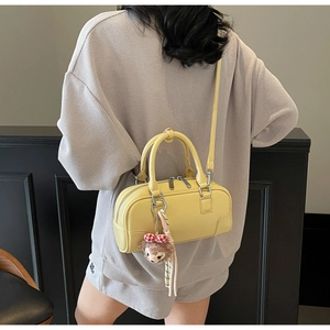 Detail of yellow boston bag with lychee texture leather and plush bear charm