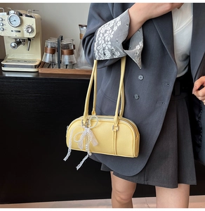 Detail of light yellow Boston bag showing fine lychee texture and lace pearl charm