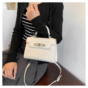 Detail of white croc-embossed kelly bag with top handle and gold-tone metal hardware lock