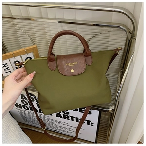 Close-up of olive nylon tote bag with textured brown leather flap and gold logo