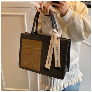 Detail of the high-capacity tote bag with dark grey canvas and brown glossy stitching