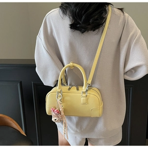 Detail of light yellow lychee grain leather pillow bag with brown plush bear charm
