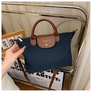 Detail of navy nylon handbag with brown leather handles and adjustable shoulder strap