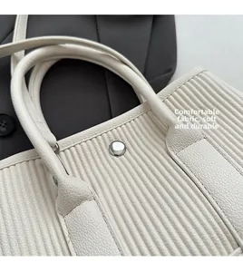 Close-up of ivory pleated tote bag showing soft fabric texture and silver metal buckle