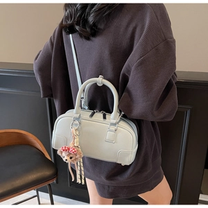 Detail of light blue pebble leather Boston bag with pink plush bear charm and strap
