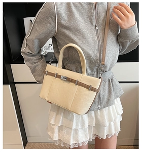 Détail du sac seau en cuir grainé beige avec fermoir tournant argenté et lanières fines