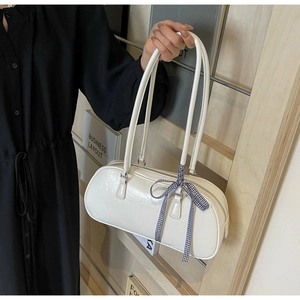 Close-up of white patent leather Boston bag with blue checkered bow and metallic hardware