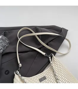 Detail of off-white pleated bag with silver chain strap and metal turn-lock buckle close-up