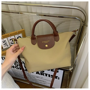 Detail of khaki nylon tote bag featuring brown lizard-textured leather flap and gold hardware