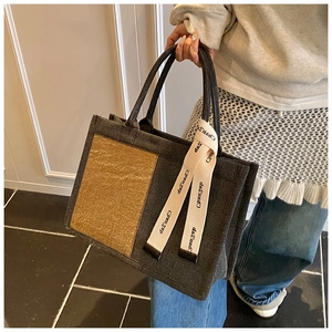 Detail of grey canvas tote bag with yellow textured pocket and branded ribbon handles