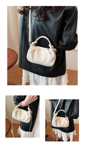 Close-up of cream pleated bucket bag showing knotted handles and detachable strap
