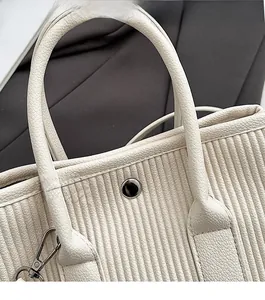 Close-up of silver snap button closure and pleated texture on white bucket bag