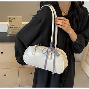 Close-up of white cracked leather cylinder bag with blue plaid ribbon bow and zipper detail
