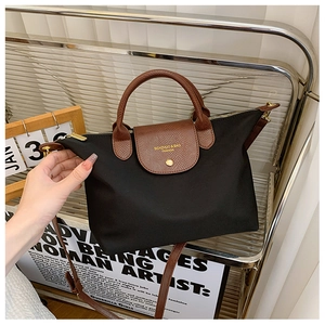 Detail of black nylon tote with brown leather flap and adjustable shoulder strap